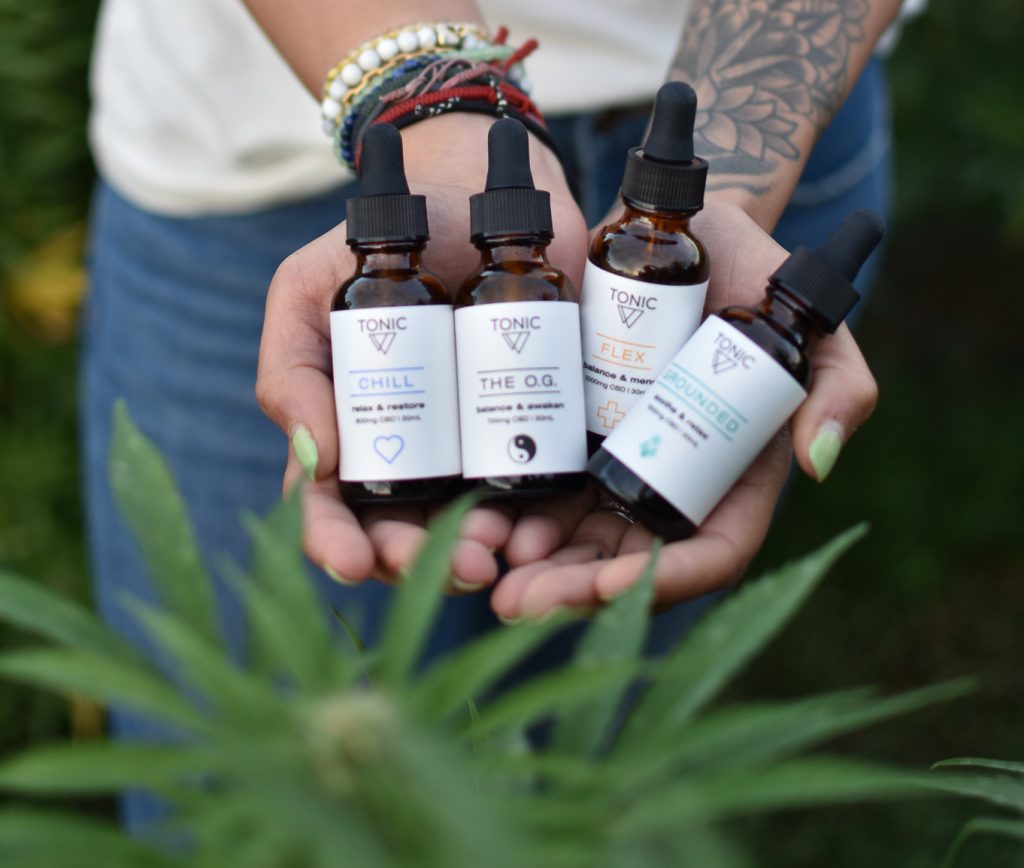 hands holding tonic cbd bottles hemp-farm