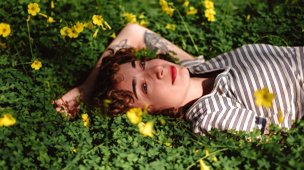 woman laying in grass with yellow flowers